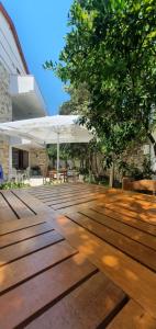 une terrasse en bois avec un parasol blanc et des arbres dans l'établissement Xho's Forest Guest House, à Berat