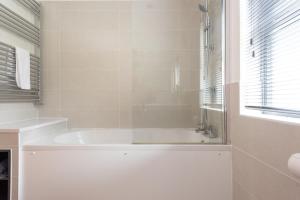 une salle de bain blanche avec une baignoire et une fenêtre dans l'établissement Blossom Lodge, 1 Roadford Lake Lodges, à Lifton 22 autres photos
