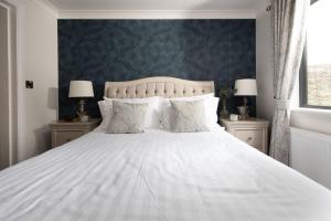 une chambre avec un lit blanc et deux lampes dans l'établissement Blossom Lodge, 1 Roadford Lake Lodges, à Lifton