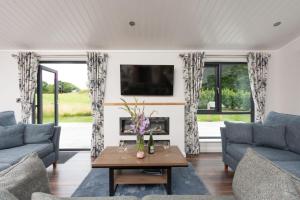 a living room with two couches and a table at Blossom Lodge, 1 Roadford Lake Lodges in Lifton