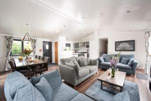 un salon avec des canapés bleus et une table dans l'établissement Blossom Lodge, 1 Roadford Lake Lodges, à Lifton
