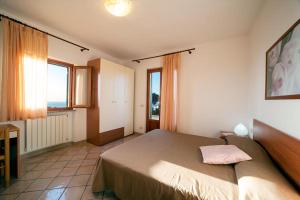 a bedroom with a large bed and two windows at Da Angiolina in Marciana