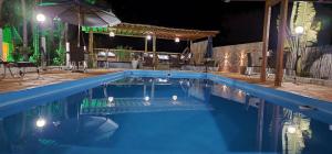 a swimming pool at night with an umbrella at Pousada Lago Azul in Delfinópolis