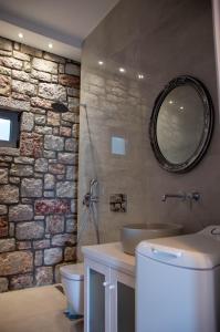 een badkamer met een stenen muur, een wastafel en een spiegel bij Villa Iliousa Grand in Psinthos