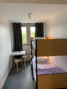 a bedroom with a bunk bed and a table and a desk at FeWo Hostel in Cologne
