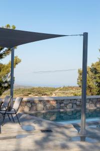 een patio met 2 stoelen en een grote parasol bij Villa Iliousa Grand in Psinthos