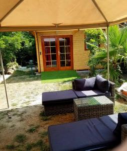 un patio con 2 sofás y una sombrilla en Normandy cottage en Gagny