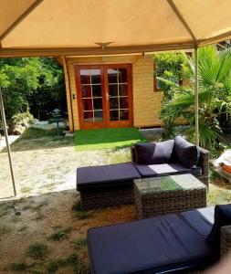 - une terrasse avec 2 canapés et un parasol dans l'établissement Normandy cottage, à Gagny