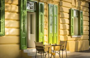 a table and chairs in front of a building with green shutters at Apartments Atlanta - Liburnia in Lovran