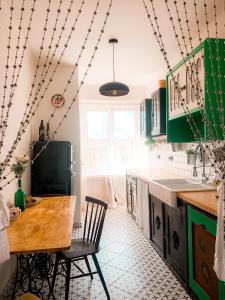 cocina con armarios verdes y mesa de madera en Kiki & Luky family apartment by Prague Castle, en Praga