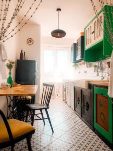 una cocina con armarios verdes, mesa y sillas en Kiki & Luky family apartment by Prague Castle, en Praga