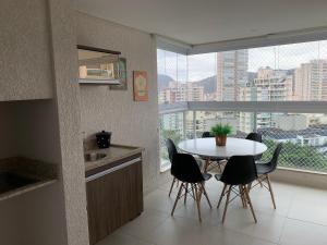 uma cozinha com mesa e cadeiras e uma janela em Apartamento Alto Padrão / prédio com piscina e quadra. no Guarujá