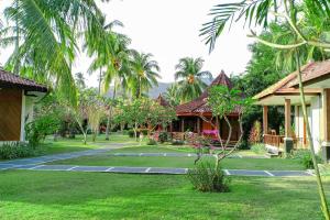 a courtyard of a resort with palm trees and houses at mascot hotel senggigi in Senggigi