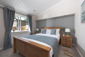 a bedroom with a large bed and a window at Orchid Lodge, 23 Roadford Lake Lodges in Lifton
