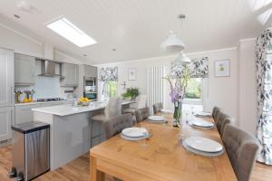 a kitchen and dining room with a wooden table and chairs at Orchid Lodge, 23 Roadford Lake Lodges in Lifton