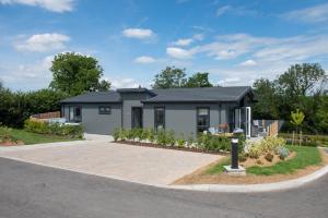 a small house in a driveway with a garden at Orchid Lodge, 23 Roadford Lake Lodges in Lifton