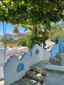 eine weiße Wand mit blauen Stühlen und einem Baum in der Unterkunft Sea Breeze in Archangelos