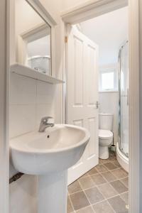 a white bathroom with a sink and a toilet at Cromer Town Apartment 1 - Norfolk Holiday Properties in Cromer