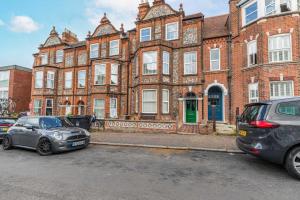 two cars parked in front of a large brick building at Cromer Town Apartment 1 - Norfolk Holiday Properties in Cromer