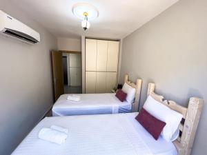 two beds in a small room with white sheets at Just Dream Suites in Kaş