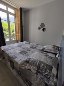 ein Schlafzimmer mit einem Bett mit einer Decke darauf in der Unterkunft Agréable T2 au centre de Luchon in Luchon