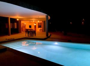 a swimming pool lit up at night with a table in the background at Palmeira Da Cruz EcoLodge in Chã da Igreja