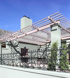 a pergola on a house with a fence at Jardin de la Ferme in Franschhoek