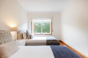 a bedroom with two beds and a window at São Félix Seaside Oasis in São Félix da Marinha