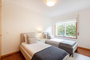 a bedroom with two beds and a window at São Félix Seaside Oasis in São Félix da Marinha