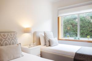 a white bedroom with two beds and a window at São Félix Seaside Oasis in São Félix da Marinha