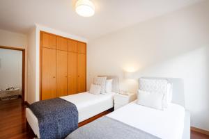 a bedroom with two beds and a cabinet at São Félix Seaside Oasis in São Félix da Marinha