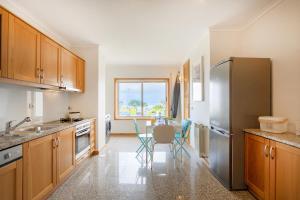 a kitchen with wooden cabinets and a stainless steel refrigerator at São Félix Seaside Oasis in São Félix da Marinha