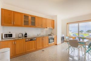a kitchen with wooden cabinets and a table in it at São Félix Seaside Oasis in São Félix da Marinha