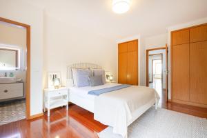 a white bedroom with a bed and a bathroom at São Félix Seaside Oasis in São Félix da Marinha