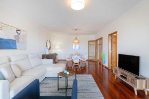 a living room with a white couch and a tv at São Félix Seaside Oasis in São Félix da Marinha