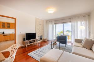 a living room with a white couch and a television at São Félix Seaside Oasis in São Félix da Marinha