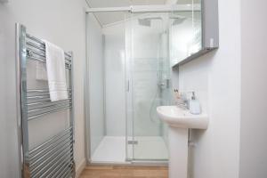 une salle de bain blanche avec une douche et un lavabo dans l'établissement Periwinkle Lodge, 3 Roadford Lake Lodges, à Lifton 16 autres photos