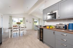 a kitchen with gray cabinets and a counter top at Periwinkle Lodge, 3 Roadford Lake Lodges in Lifton