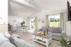 a living room with a couch and a table at Periwinkle Lodge, 3 Roadford Lake Lodges in Lifton