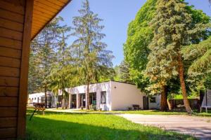 a building with trees in front of a yard at Domki Skowronki in Kąty Rybackie