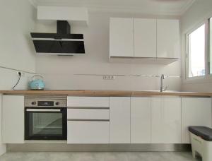 a kitchen with white cabinets and a sink and a stove at El Vitoriano in Roquetas de Mar