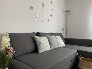 a gray couch in a living room with a clock on the wall at Begoña Centro by FlowHome in Gijón
