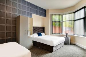 a bedroom with two beds and two windows at OYO The Longlands Hotel in Middlesbrough