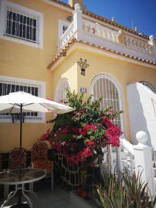un edificio con tavolo, sedie e fiori di Casa JIRAFA con la vista a Gran Alacant