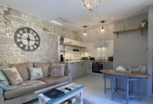 a living room with a couch and a clock on the wall at Granary Cottage in Weymouth
