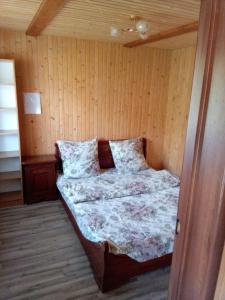 a bed in a room with a wooden wall at Sadyba u Vani in Volovets