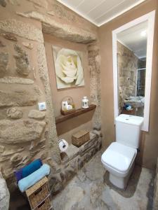 a bathroom with a white toilet in a stone wall at A Cuadriña in Mazaricos