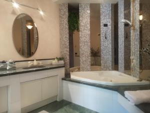 a bathroom with a tub and a sink and a mirror at ABC Rooms in Valdobbiadene