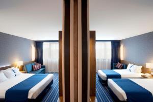 Dos camas en una habitación de hotel con azul y blanco en Holiday Inn Express Lisbon Airport, an IHG Hotel, en Lisboa