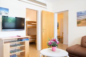 a living room with a television and a table with flowers at Ferienhof Kluvetasch Appartement Nr 2 - Strandmuschel in Rettin +8 photos
